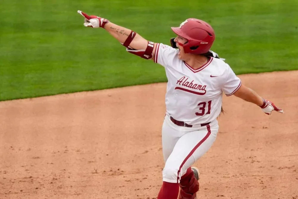 Alabama batter Alexis Pupillo points her right index finger at softball alumni in the left field stands as she celebrates a two-run homer.